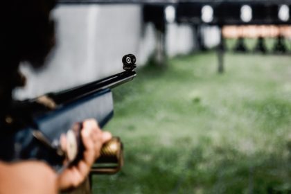 Ljudska ruka drži pušku ciljajući metu (discipline u streljaštvu)