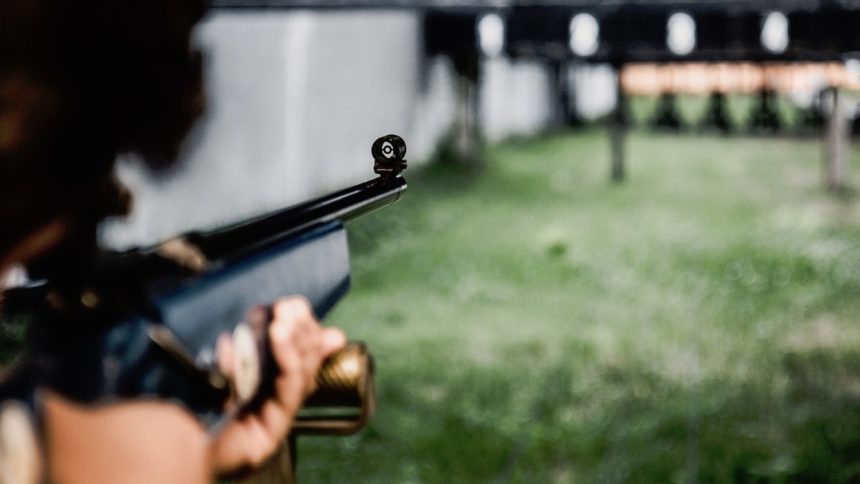 Ljudska ruka drži pušku ciljajući metu (discipline u streljaštvu)
