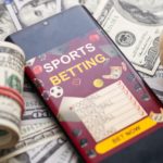 Mobitel s natpisom 'sports betting' na hrpi novaca (kako kladionice određuju koeficijente)