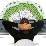 Osoba sjedi ispred monitora i novčanica (kako kladionice zarađuju)