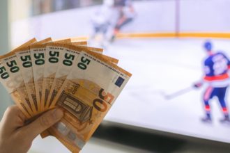 Osoba drži novčanice na hokej utakmici (kako se kladiti na hokej)